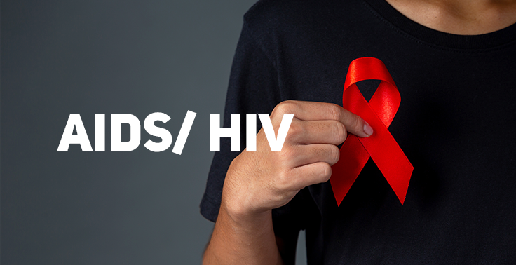 Pessoa vestindo camiseta preta segurando um laço vermelho, símbolo da conscientização contra a AIDS, próximo ao peito. Ao lado esquerdo, sobre um fundo cinza, está escrito AIDS/ HIV em destaque.