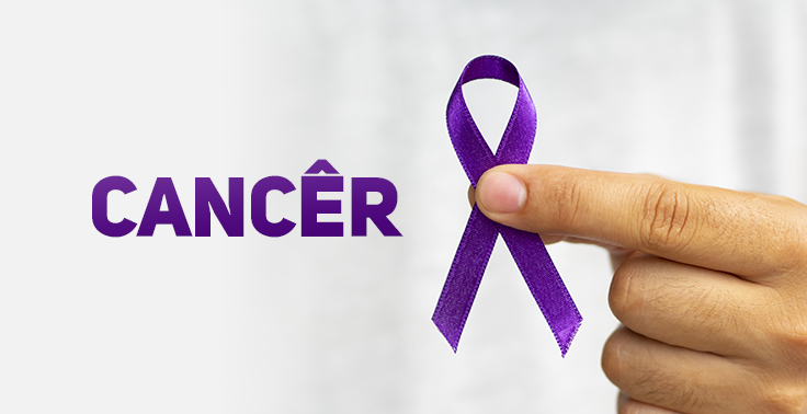 Imagem com a palavra 'CÂNCER' em destaque, na cor roxa, ao lado de uma mão segurando um laço roxo entre o polegar e o indicador. O fundo é desfocado em tons claros, destacando o símbolo de conscientização e apoio às pessoas afetadas pelo câncer.