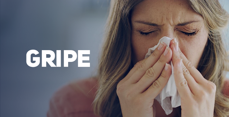 Imagem informativa de saúde com a palavra GRIPE em letras maiúsculas brancas no lado esquerdo. No lado direito, uma mulher loira está com os olhos fechados e segura um lenço de papel branco cobrindo o nariz e a boca, indicando estar assoando o nariz ou espirrando.